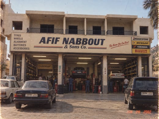 The Afif Nabbout & Sons Co. branch in Batroun in 2002, a two-storey building with its sign above three open service bays, cars raised on the lifts and staff at work