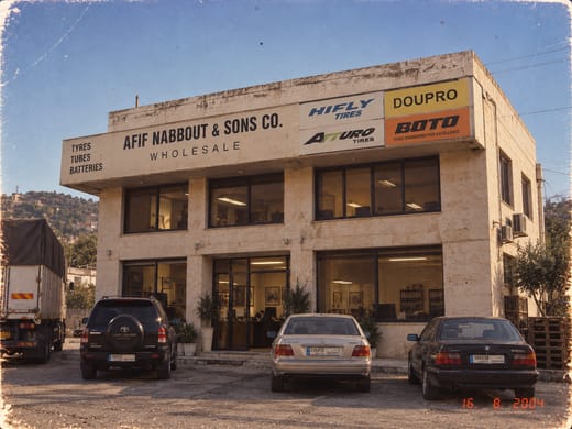 The Afif Nabbout & Sons Co. wholesale branch in 2004, a two-storey stone building signed Wholesale, with a lorry at the side and cars parked in front
